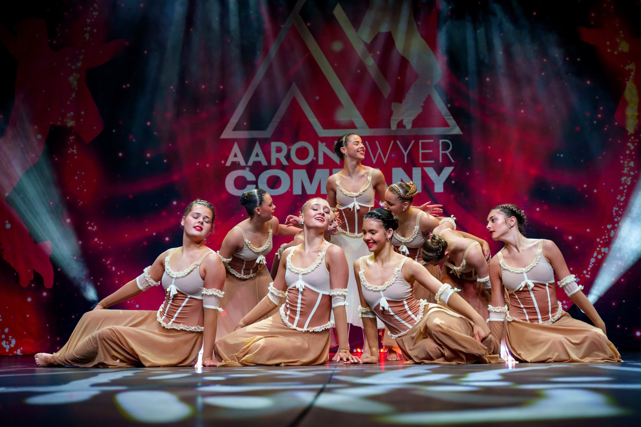 Dancers in neutral costumes gathered in a graceful stage formation.