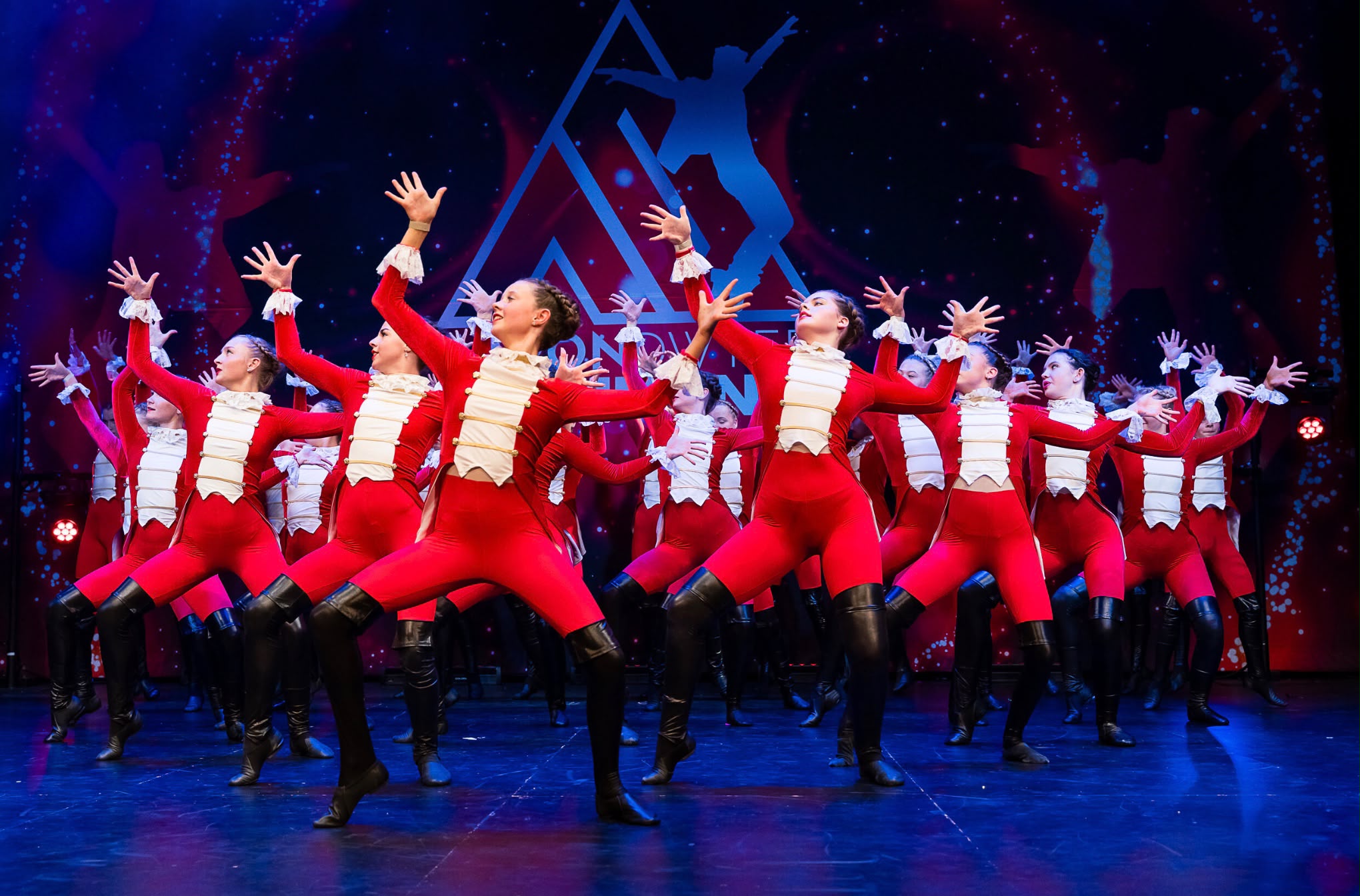 Large ensemble of dancers in red costumes performing in formation.